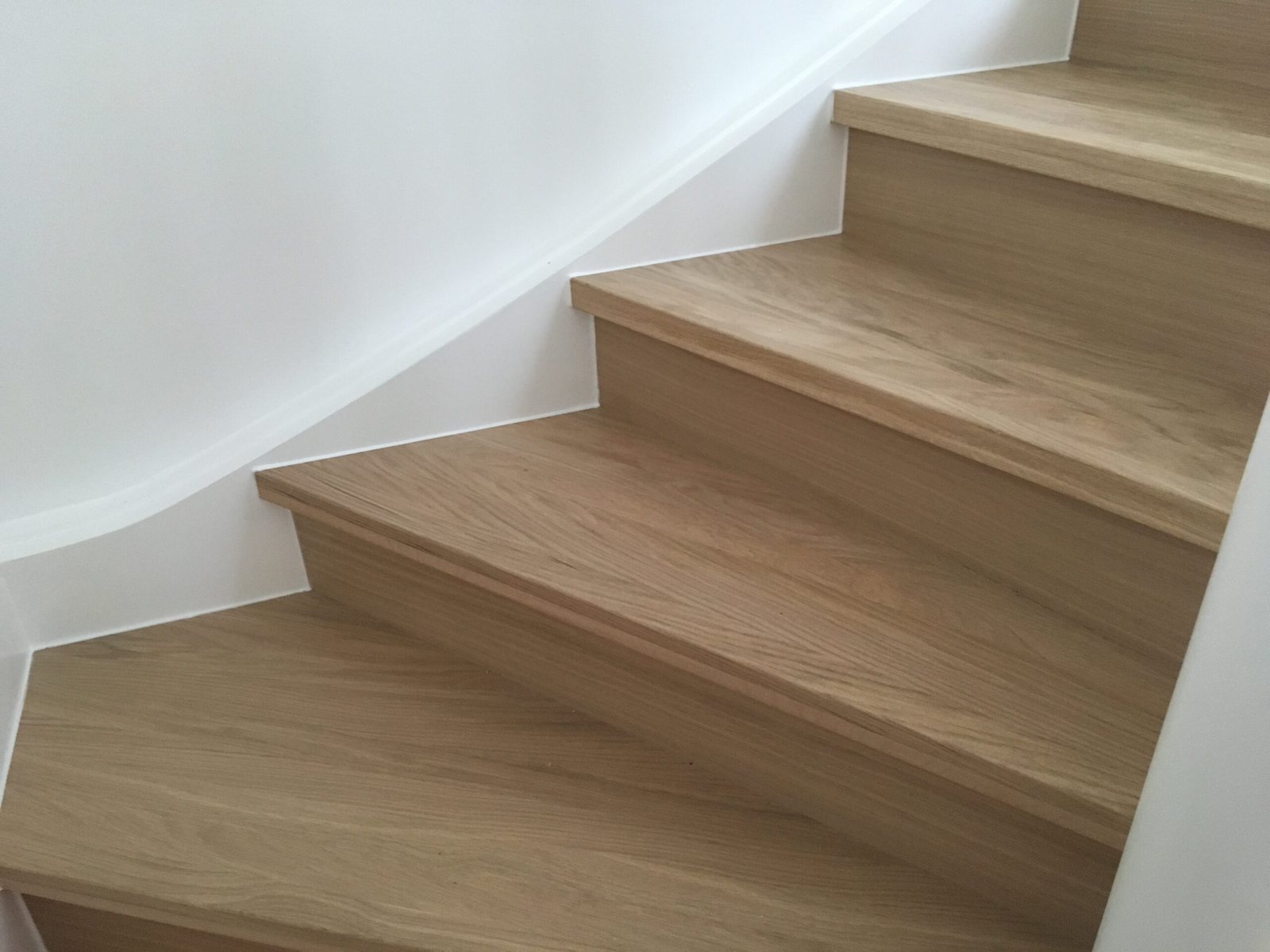 Treppe mit aufgedoppelten Eichenstufen, die an die Wandkontur angepasst sind