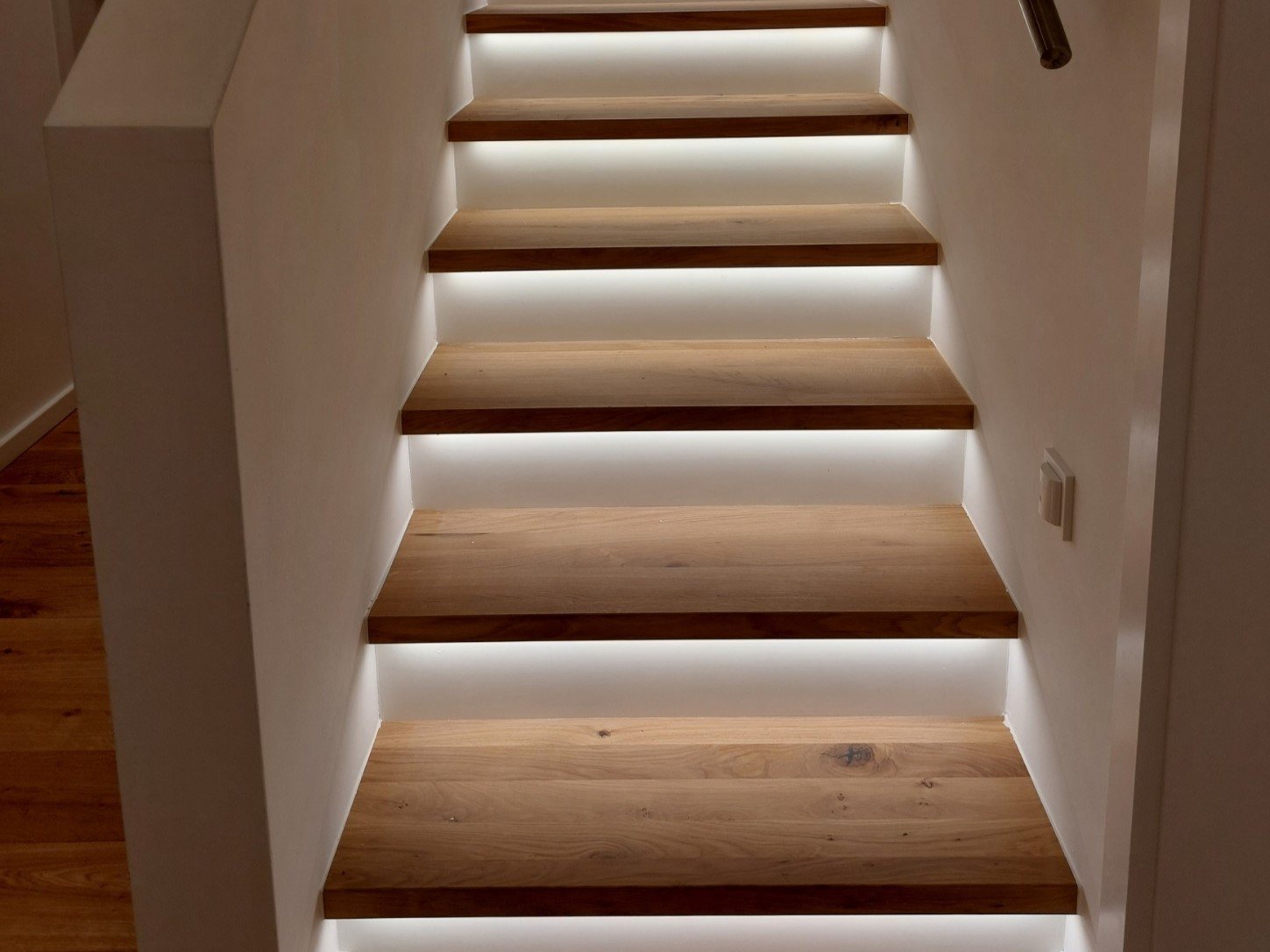 Treppe mit Eichenstufen, unter denen eine Beleuchtung sitzt